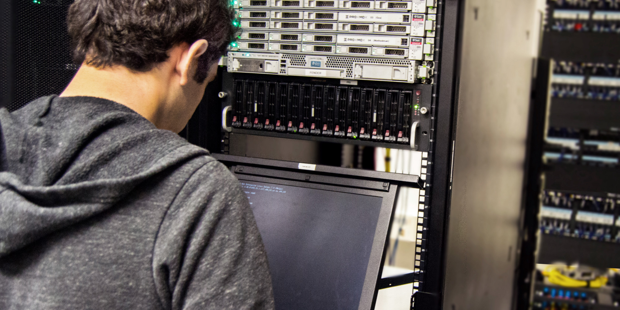 A CSH member stands at a terminal in the CSH server room